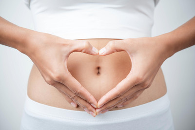 Symbolbild: Frau zeigt mit Hand Herz vor dem Bauch